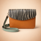 Orange crossbody bag with zebra pattern strap on a beige background