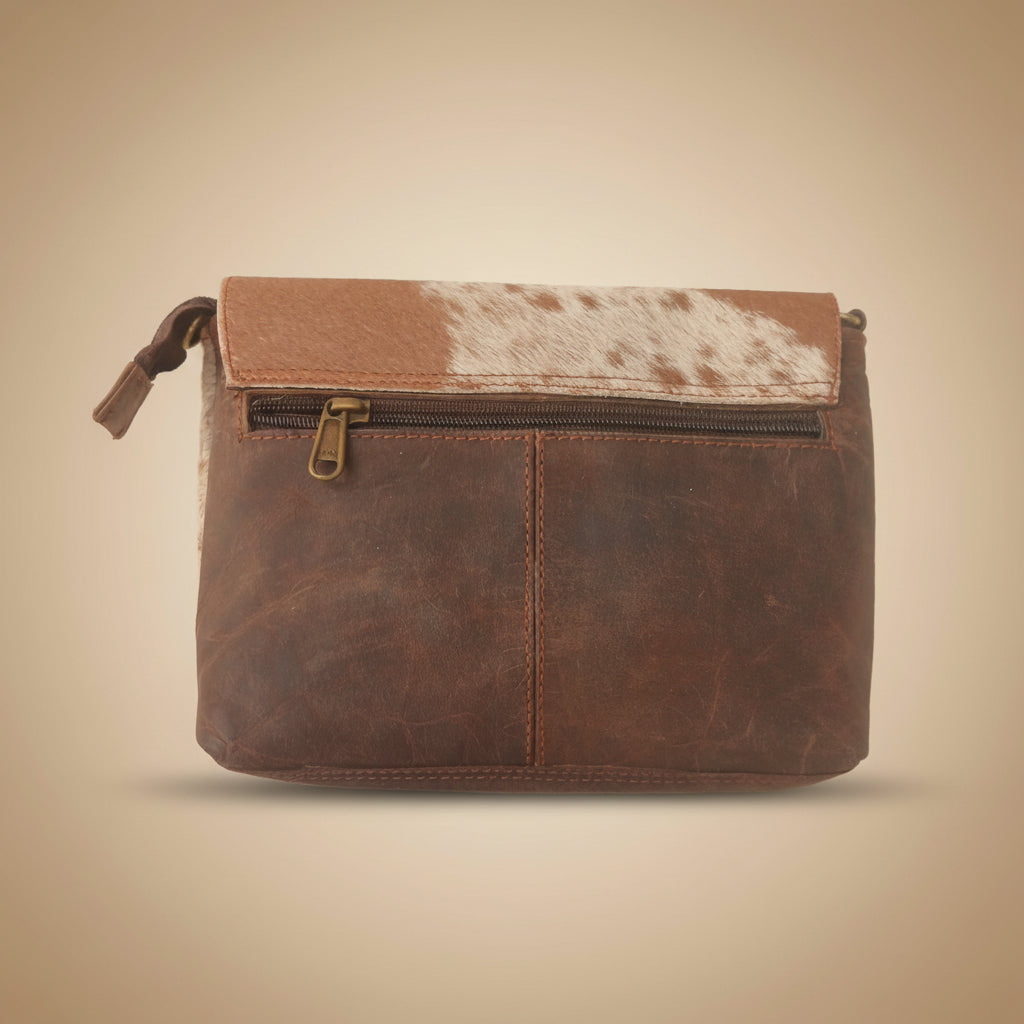 Brown leather pouch with cowhide pattern on a beige background
