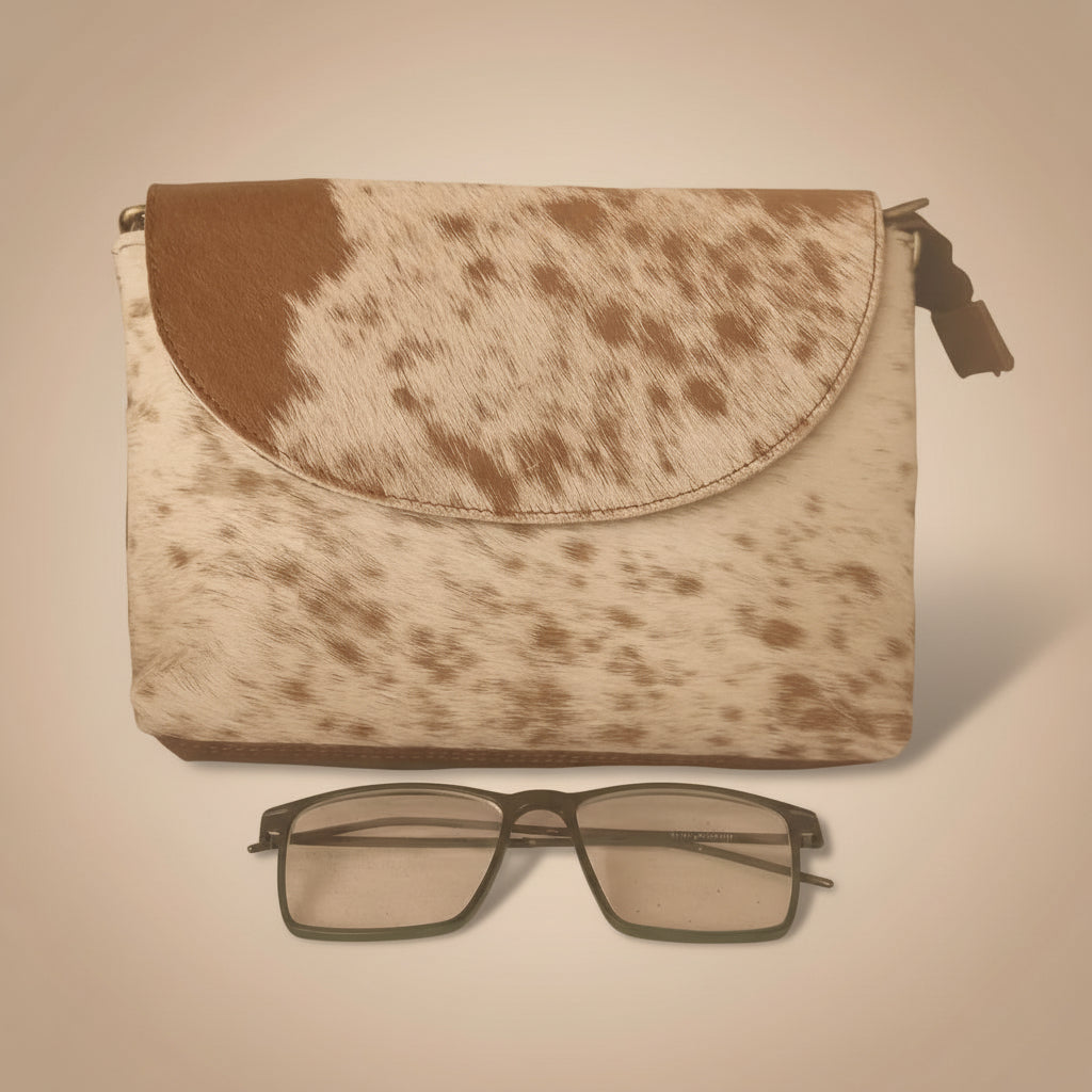 Cowhide leather pouch with a pair of glasses on a beige background
