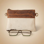 Brown leather case with gold clasps and a pair of glasses on a white background