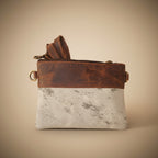 Brown leather pouch with strap on a textured white surface