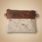 Brown leather pouch with gold ring on a textured white surface