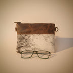 Leather case with cowhide pattern and glasses on a light gray background