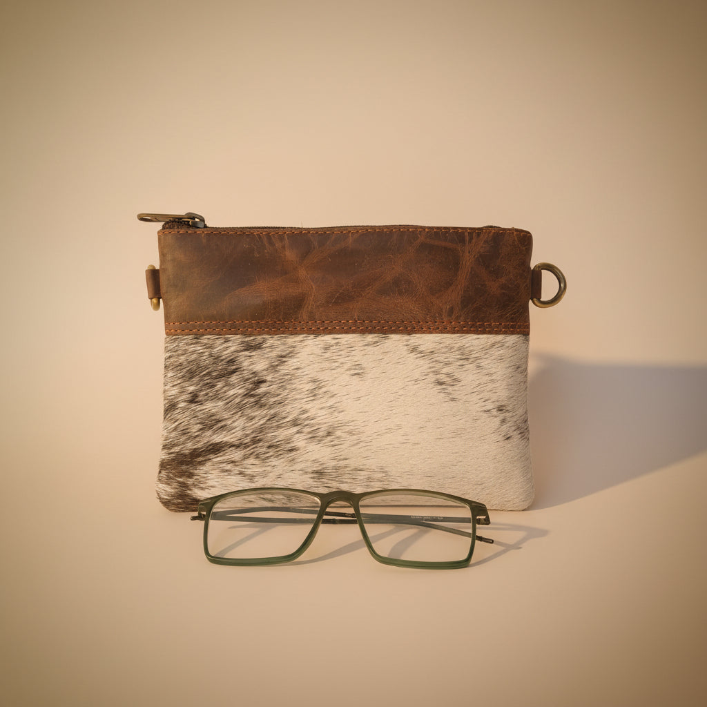 Leather case with cowhide pattern and glasses on a light gray background