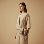 Woman holding a crossbody bag against a beige background