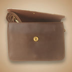 Brown leather clutch bag with a gold button on a white background