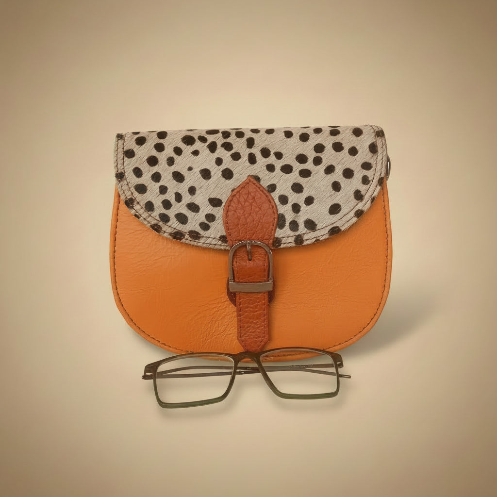 Small leather pouch with polka dot flap and glasses on a white background