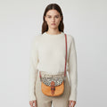 Small orange bag with a patterned flap on a light gray background