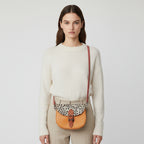 Small orange bag with a patterned flap on a light gray background