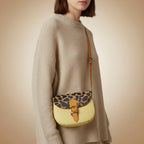Leather handbag with leopard print top flap on a beige background