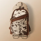 Cow print bag with a zipper and glasses on a white background