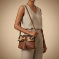 Brown leather handbag with leopard print flap on a beige background