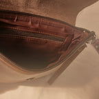 Close-up of a brown leather bag with a zipper on a light background