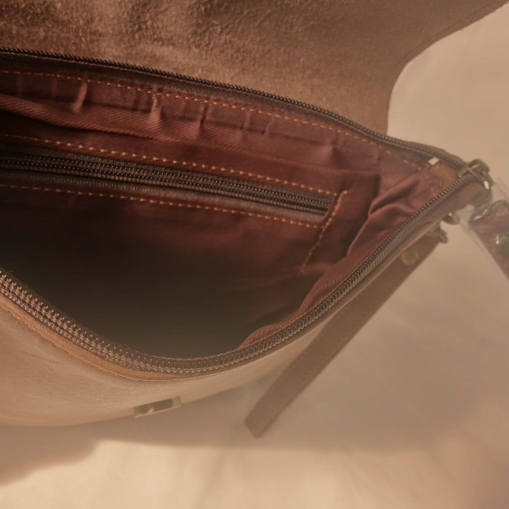 Close-up of a brown leather bag with a zipper on a light background