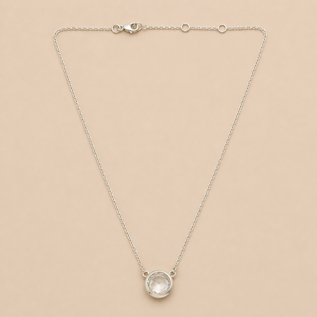 Silver necklace with a round pendant on a beige background