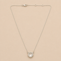 Silver necklace with a round pendant on a beige background