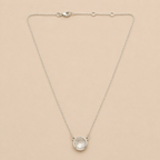 Silver necklace with a round pendant on a beige background
