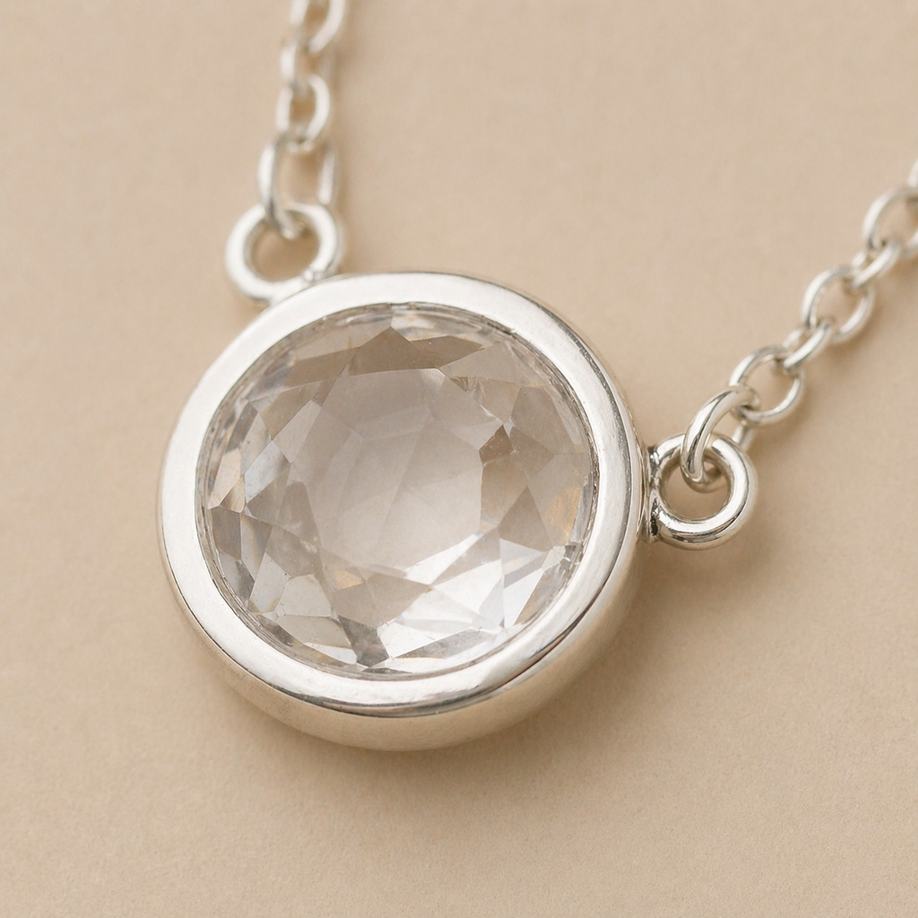 Silver necklace with a round crystal pendant on a beige background