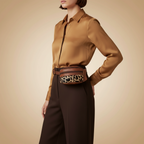 Person wearing a brown shirt and dark pants with a leopard print belt bag on a beige background