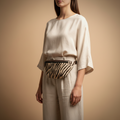 Woman wearing a zebra print belt bag against a beige background
