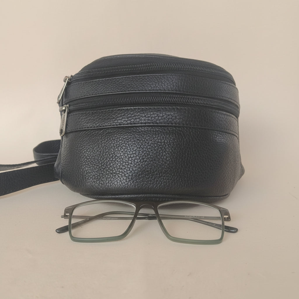 Black leather pouch with a pair of glasses on a beige background