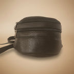 Black leather bag with a strap on a beige background