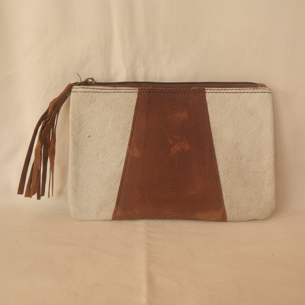Clutch bag with brown leather accent and tassel on a light gray background