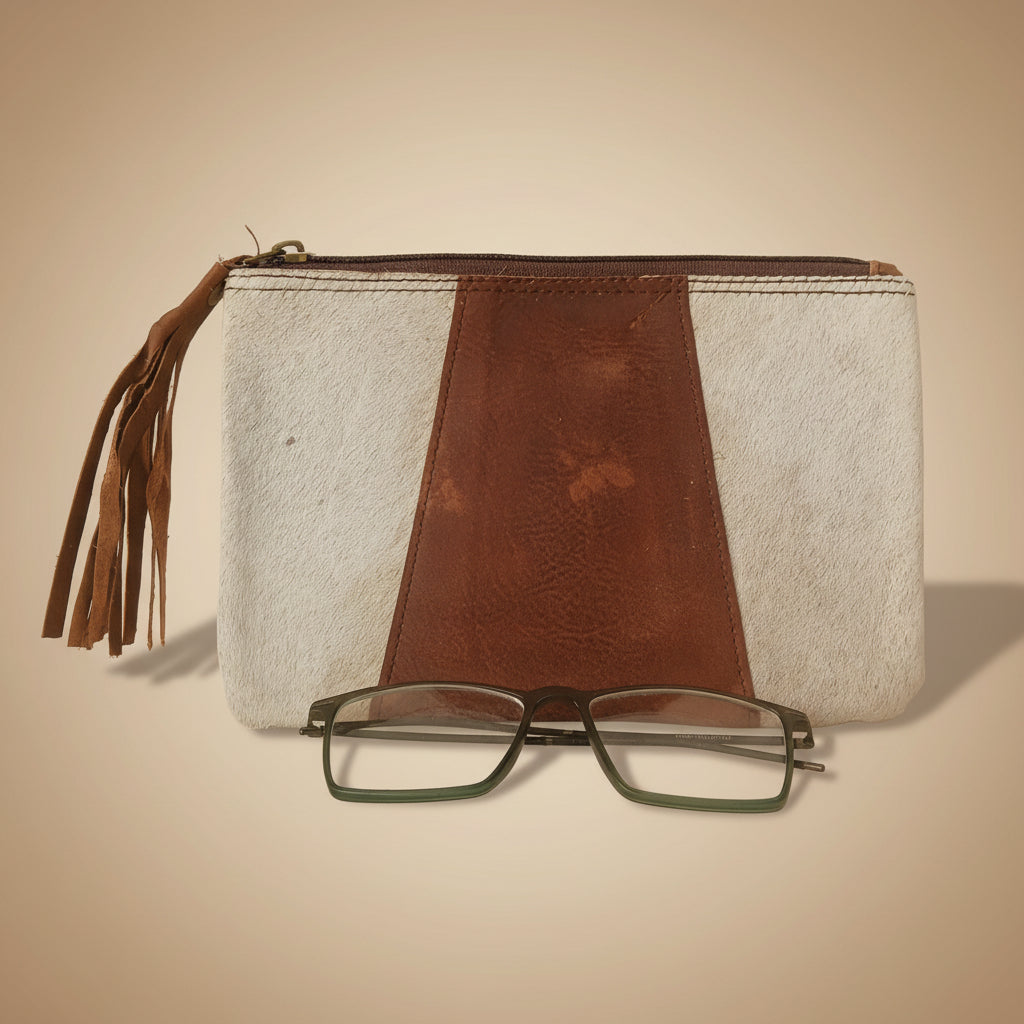 Brown leather clutch with tassel and glasses on a white surface