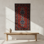 Decorative rug with geometric pattern on a white wall above a wooden bench