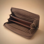 Close-up of a brown leather wallet with visible stitching on a light gray background