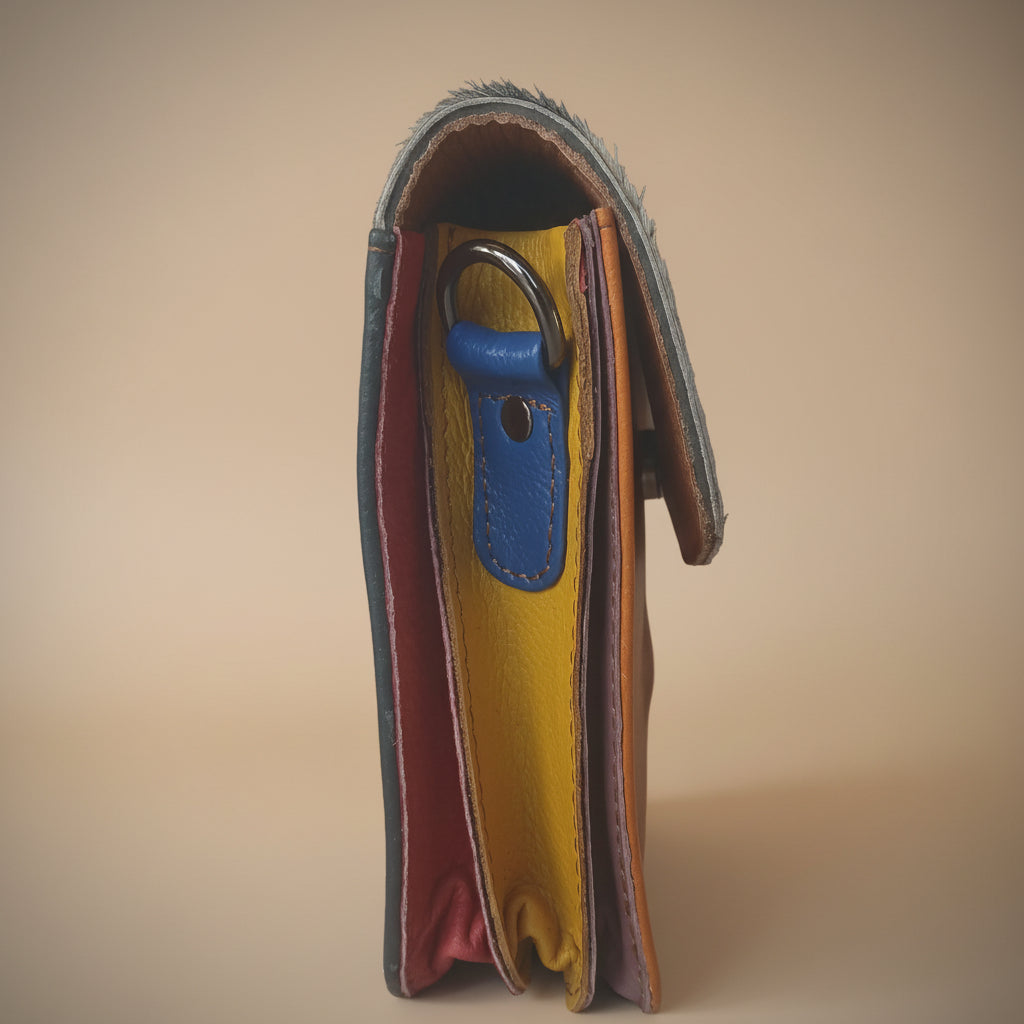 Multicolored leather wallet with a blue keychain on a beige background