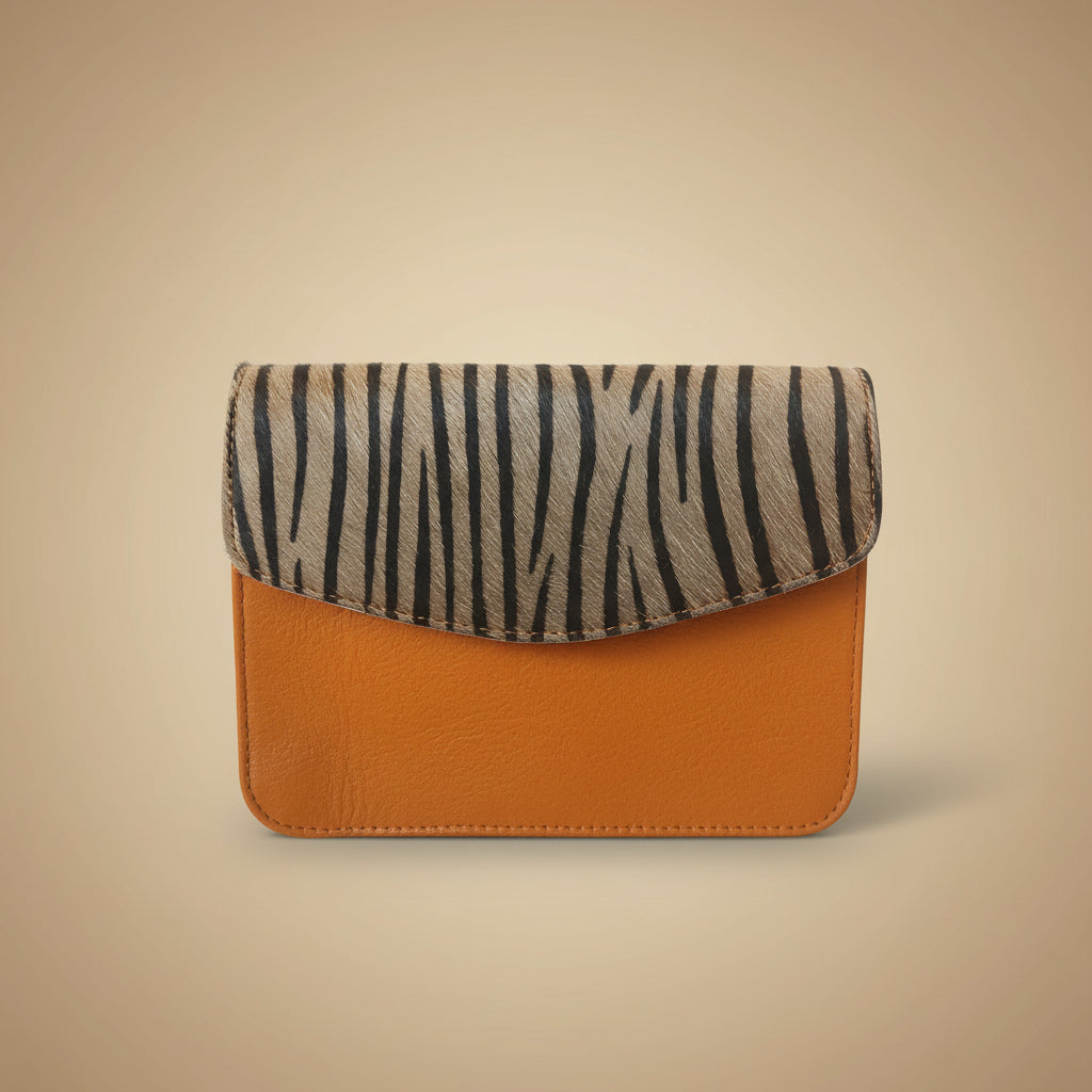 Phone case with zebra pattern on one side and brown leather on the other, on a light background