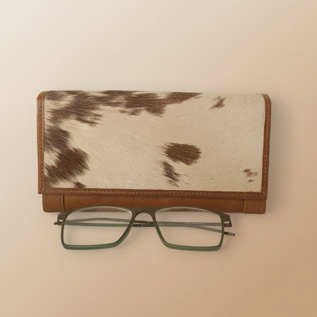 Cow print wallet with a pair of glasses on a white background