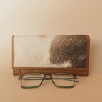 Wallet with cowhide pattern and glasses on a white background