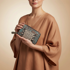 Woman holding a clutch with leopard print and floral pattern against a beige background