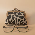 Giraffe-patterned case with a pair of glasses on a light gray background