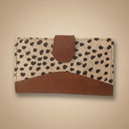 WALLET CLUTCH with spotted pattern and brown leather accents on a light gray background