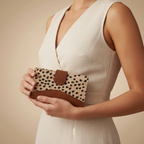Woman holding a clutch with leopard print design against a beige background