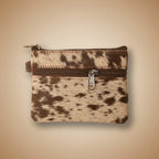 Small pouch with cowhide pattern and zipper on a light gray background