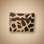 Small pouch with cow print pattern on a light gray background