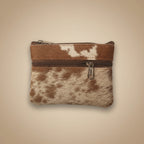 Small pouch with brown and white cowhide pattern and zipper on a light gray background
