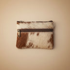Small pouch with brown and white cowhide texture and zipper on a light gray background