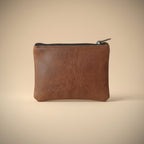 Brown leather pouch with a zipper on a light gray background