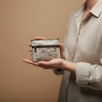 Person holding a small, patterned pouch against a beige background