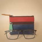 Colorful zippered pouch with a pair of glasses on a light gray background