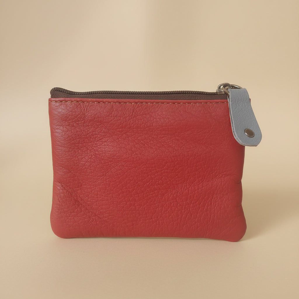 Red leather coin purse with a gray zipper on a white background