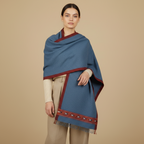 Woman wearing a blue shawl with red trim on a beige background