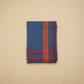 Folded blue fabric with red and orange stripes on a beige background
