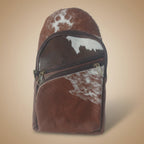Brown and white cowhide patterned pouch with a zipper on a white background