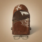 Brown leather bag with cowhide pattern and glasses on a white background